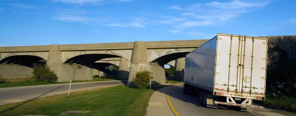 A semi truck driving under a bridge